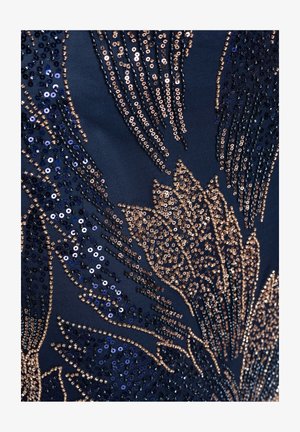 Tummansininen kangas, jossa on monimutkainen kultaisten ja laivastonsinisten paljettikukkien kirjailu, joka muodostaa yksityiskohtaisia terälehtimuotoja.