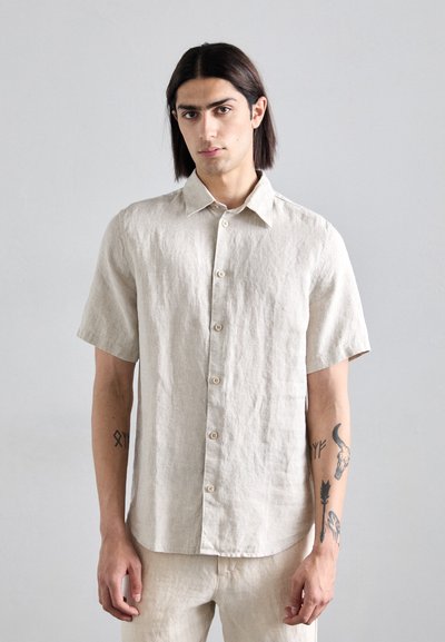 Chemise à manches courtes beige en lin avec un col et un ourlet droit. Équipée de boutons en bois et d'une coupe décontractée.