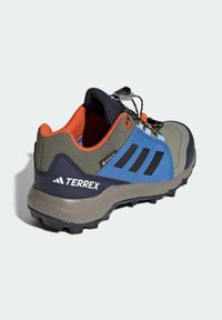 Buty trekkingowe Terrex w wielokolorowym wzorze, łączące szare, niebieskie i pomarańczowe materiały. Cholewka o fakturze, solidna podeszwa oraz system szybkiego sznurowania.