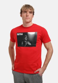 Röd bomullströja med en svartvit grafisk tryck från "Escape from New York." Crew neck-design med korta ärmar.