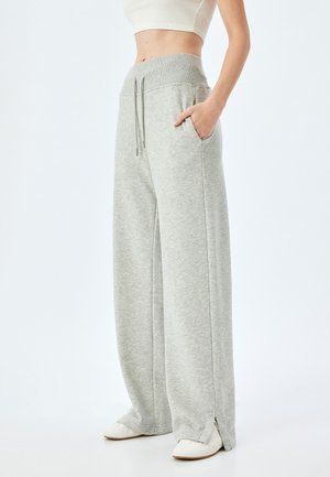 Lichtgrijze wijde sweatpants met een ribbelband, trekkoord, zijzakken en splitten aan de onderkant. Gemaakt van zachte, gestructureerde stof.