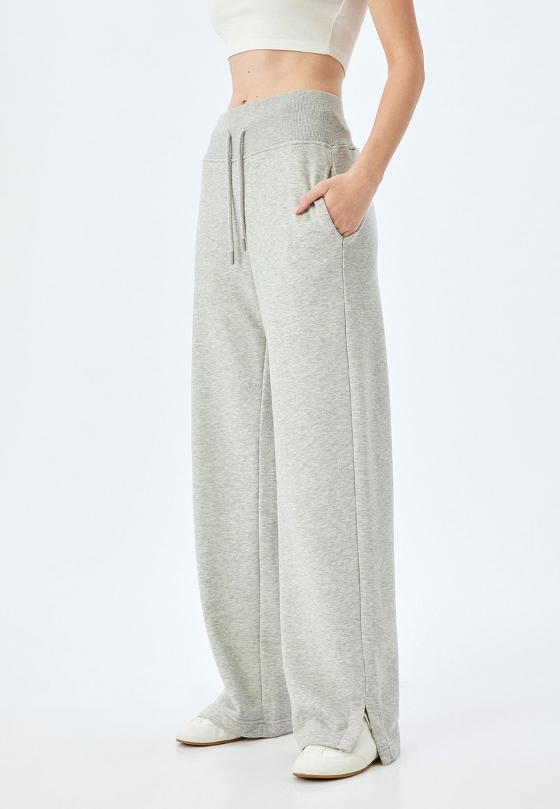 Lichtgrijze wijde sweatpants met een ribbelband, trekkoord, zijzakken en splitten aan de onderkant. Gemaakt van zachte, gestructureerde stof.
