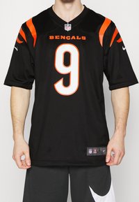 Czarna koszulka NFL z pomarańczowymi akcentami, z numerem 9 i napisem "BENGALS". Wykonana z tkaniny, z krótkimi rękawami i dekoltem w szpic.