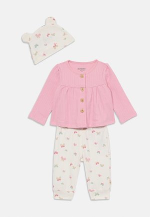 Top de manga larga de canalé rosa con botones de madera, combinado con pantalones blancos con patrones de lazos en tonos pasteles y un gorro a juego con orejas de oso.
