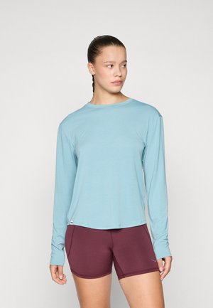Light blue long-sleeve shirt with a rounded neckline, paired with maroon fitted shorts. Fabric appears smooth and lightweight.