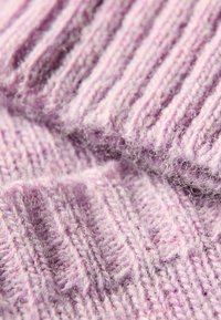 Heller lila gestrickter Stoff mit einer gerippten Textur und weicher, flauschiger Oberfläche. Sichtbare Stiche mit leichtem Glanz.