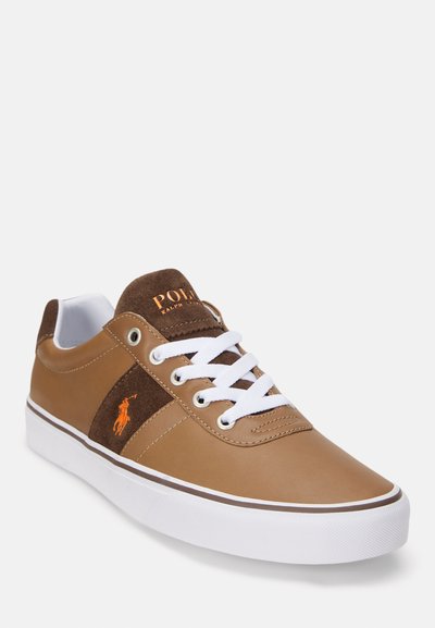 Καφέ δερμάτινο και σουέτ αθλητικό παπούτσι με λευκές κορδόνες, λογότυπο, ελαστική σόλα, και αντίθετη καφέ ρίγα. Στρογγυλή μύτη και casual σχέδιο.