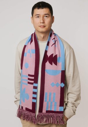 Wielobarwny szalik z geometrycznymi wzorami w kolorach różowym, niebieskim i bordowym, z frędzlami na krawędziach i miękką fakturą, zawiązany wokół szyi.