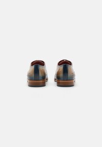 Scarpe eleganti in pelle marroni e blu navy con una finitura liscia, punte arrotondate e tacco in legno. Cuciture discrete sul retro.