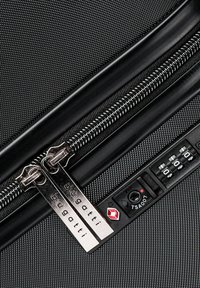Schwarze, strukturierte Stoffkoffer mit doppelt metallen Reißverschlüssen, Markenanhängern und einem TSA-zugelassenen Zahlenschloss an der Seite.