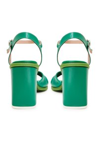 Groene leren haksandalen met een blokhak, open teen, enkelband en een contrasterende lichtgroene zool. Glad materiaal, eenvoudig ontwerp.