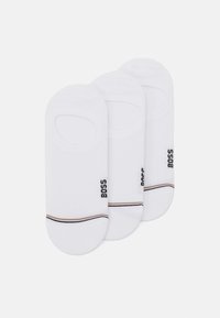 Trois paires de chaussettes blanches coupe basse en coton. Chaque chaussette présente une ouverture ronde, avec un logo noir et une rayure colorée près de la cheville.