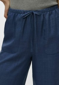 Navyblauwe, lichtgewicht, geweven stoffen broek met een elastische tailleband en trekkoord, voorzien van twee grote voorzakken.