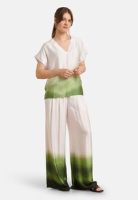 Zijden mix outfit met een kort mouwtop met een V-hals, die overgaat van wit naar groen, gecombineerd met wijde broekspijpen in een vergelijkbare gradient.