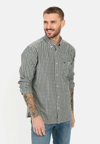 Karierte Button-Up-Bluse in Navy und Weiß, aus Baumwolle. Verfügt über eine Brusttasche, lange Ärmel und einen abgerundeten Saum.