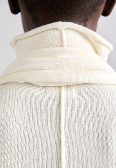 Pull en maille crème avec col rabattu et détail de couture à l'arrière. Présente un motif texturé et un tissu lisse et doux.
