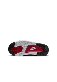 La semelle de la chaussure Nike présente un caoutchouc noir avec des accents blancs et rouges, des motifs texturés pour l'adhérence, et un logo blanc bien en évidence.