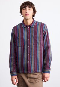 Multi-colored shirt featuring vertical stripes in maroon, blue, and green. Includes two chest pockets and button-up front with a collar.