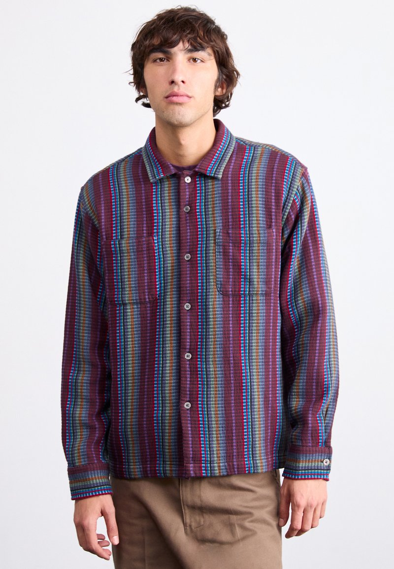 Multi-colored shirt featuring vertical stripes in maroon, blue, and green. Includes two chest pockets and button-up front with a collar.