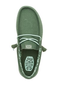 Zapato tipo slip-on de color verde oscuro con tejido texturizado, cordones de color verde claro y forro estampado. Presenta un logo en la plantilla y costuras reforzadas.