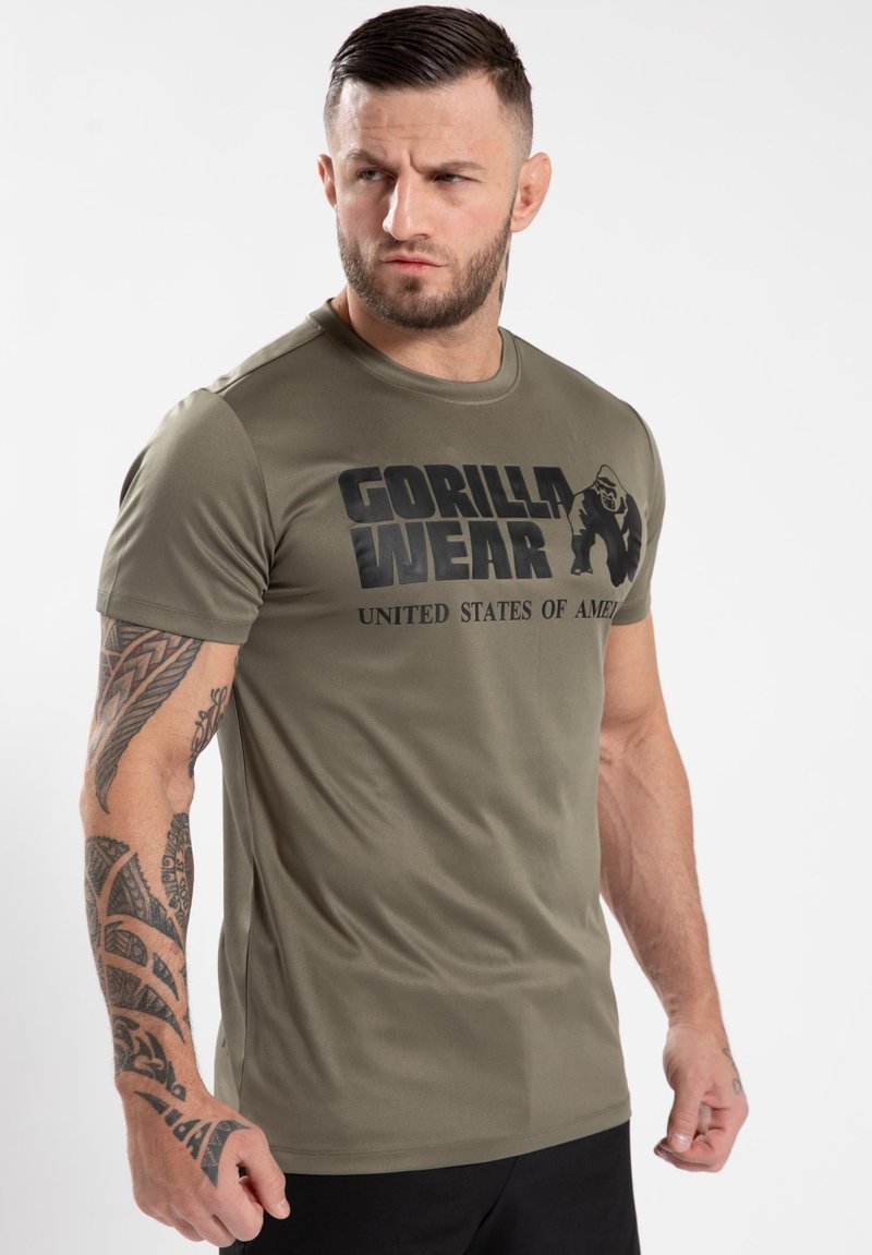 Maslinasto zeleni majica kratkih rukava s crnim ispisanim tekstom "GORILLA WEAR UNITED STATES OF AMERICA." Glatka tkanina i prilagođen dizajn.