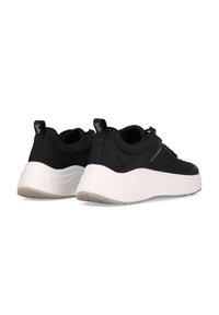 Schwarze Sportschuhe mit einer strukturierten Oberseite, einer dicken weißen Sohle und Schlaufen an der Ferse. Einfaches Design mit minimaler Markenkennzeichnung.