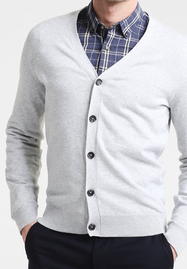 Ljusgrå cardigan med V-ringning, svarta knappar, ribbade ärmslut och nederkant, bärs över en marinblå rutig skjorta med vita detaljer.