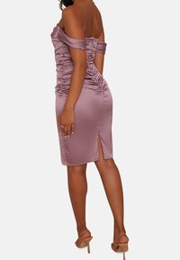 Off-the-shoulder, figurerad klänning i mjuk lavendelfärgad tyg, med drapering längs sidorna och en hög skårning på baksidan.