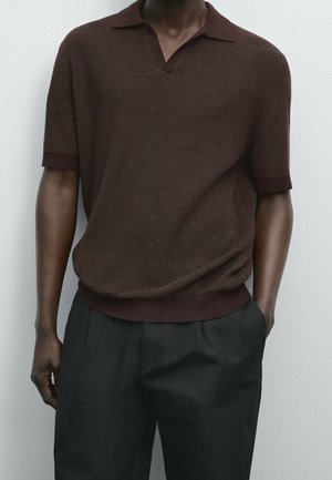 Brun kortærmet strikket polo med V-hals og ribbede kraver og manchetter, parret med skræddersyede sorte bukser.