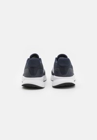 Navy athletic shoes with a fabric upper, padded collar, and white midsole; textured sole for grip; minimalist design with no visible branding.