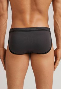 Zwarte herenboxershorts met een zachte, gladde textuur. Bevat een contrasterende tailleband en een strak, minimalistisch ontwerp, wat het comfort en de pasvorm verbetert.