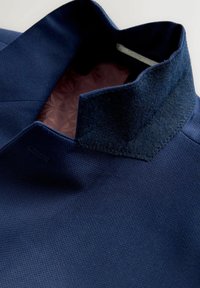 Tengerészkék dzseki texturált anyagból, kontrasztos filc gallérral és sötétebb árnyalatú mintás béléssel.