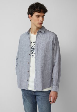 Lichtblauw en wit gestreept katoenen overhemden met een ontspannen pasvorm, lange mouwen en een klassieke kraag; gecombineerd met een wit T-shirt eronder.