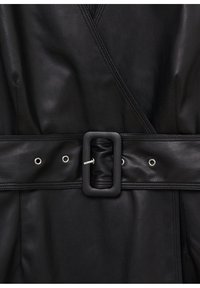 Vêtement en cuir noir avec un design croisé, large ceinture avec une boucle rectangulaire, œillets métalliques et texture lisse.