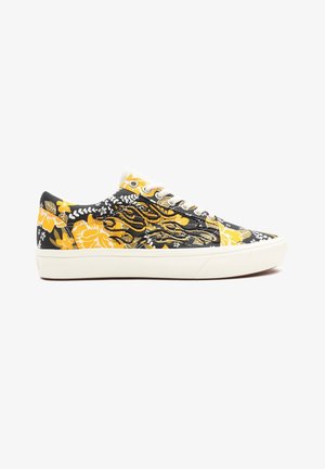 Niski sneaker z czarno-żółtym kwiatowym wzorem, białymi sznurowadłami i czarnym haftowanym motywem płomienia po boku. Biała gumowa podeszwa.