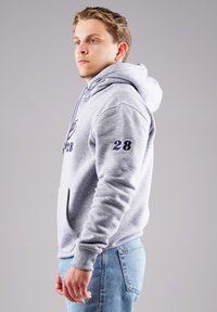 Grauer Kapuzenpullover mit Fronttasche und gestickter "28" auf dem Ärmel. Glatte Textur, normale Passform, mit Kordelzug am Hals.