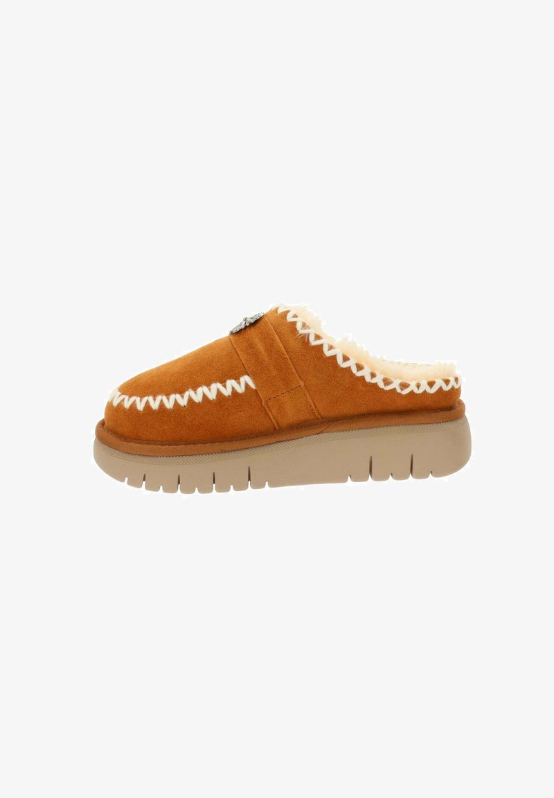 Scarpa slip-on in suede tan con cuciture bianche, interno morbido e suola spessa in gomma beige. Presenta dettagli decorativi sul lato.