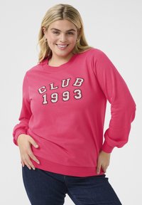 Vaaleanpunainen huppari, jossa on valkoisella ja harmaalla brodattu "CLUB 1993", klassinen pyöreä kaula-aukko ja ribatut hihansuut sekä helma.