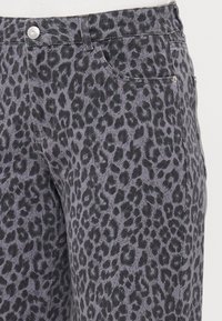 Džínsy s leopardím vzorom, s šedým pozadím a čiernymi škvrnami, so strieborným gombíkom a prednými vreckami. Štruktúrovaný povrch.