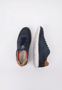 Zapatos de ante azul marino con suela blanca y detalle de cuero marrón en el talón, con punta redonda y diseño de cordones.