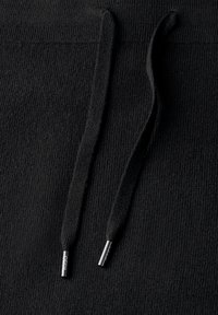 Gros plan sur un tissu de sweat-shirt noir présentant une surface texturée et deux cordons avec des embouts en métal.