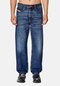 Baggy blue denim jeans with light fading, contrasting stitching, five-pocket design, and a button closure at the waistband.