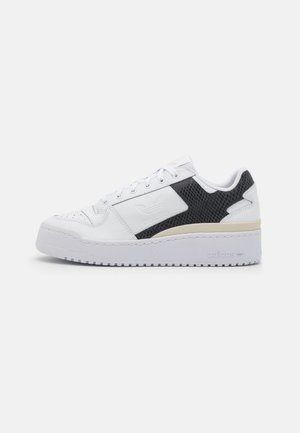 Baskets basses blanches Adidas avec panneau latéral texturé noir, semelle épaisse et fermeture à lacets, vues du côté extérieur.