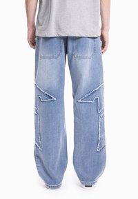 Jeans z širokimi hlačnicami v svetlo modrem denim materialu, z namerno poškodovanimi predelki in cofki, z dvema zadnjima žepoma in ohlapnim krojem.