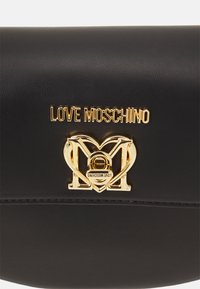 Sac en simili cuir noir avec un logo doré "LOVE MOSCHINO" et un emblème en forme de cœur avec un design de verrou intégré.