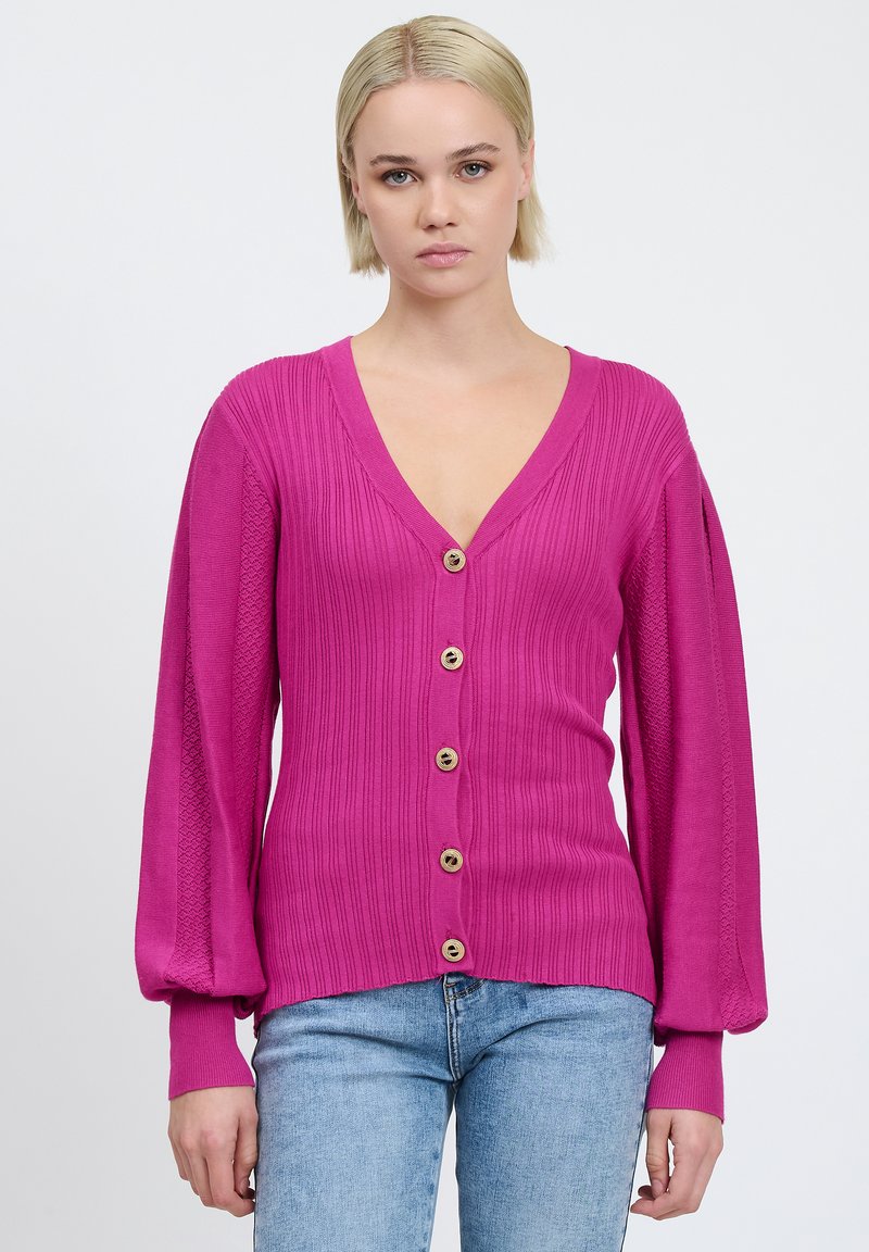 Fuchsia strikjakke med dyb V-hals, struktureret ribbet design, lange pufærmer og fem gyldne runde knapper ned foran.