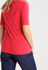 Kortærmet lyserød t-shirt med rund halsudskæring og blød tekstur, parret med mørkeblå denimbukser. Pasformen er afslappet og uformel.
