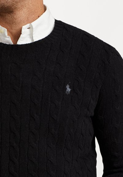 Crni pleteni pulover izrađen od mekanog materijala, s okruglim izrezom i malim izvezenim logotipom na prsima.