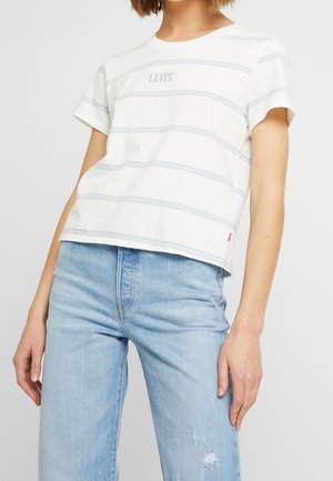 Person wearing a white Levi's t-shirt with thin gray stripes and light blue high-waisted jeans with slight distressing on one thigh.