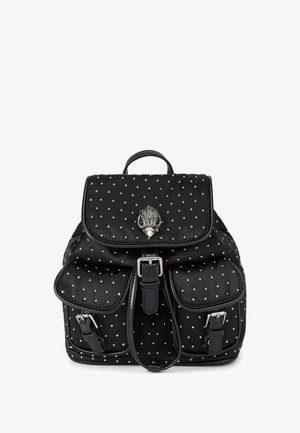 Sac à dos noir avec des clous argentés, deux poches avant à boucles, un rabat avec une fermeture décorative en forme de tête d'animal argentée, et une poignée supérieure.